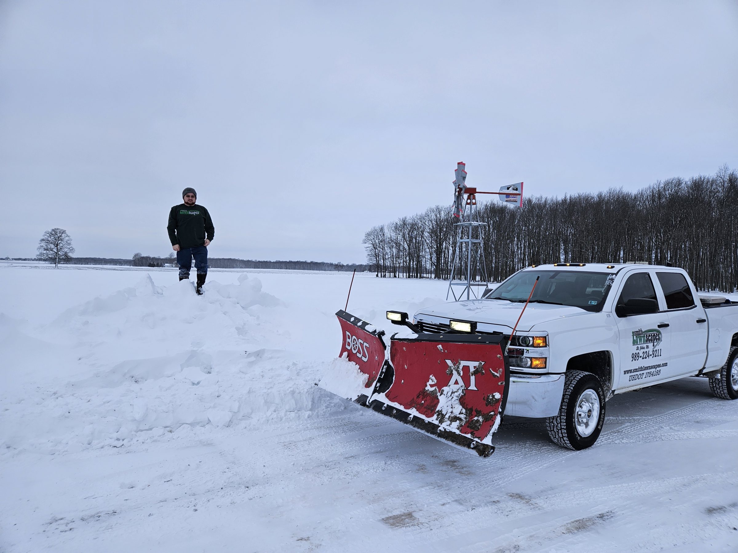 Truck with plow clearing snowy field.