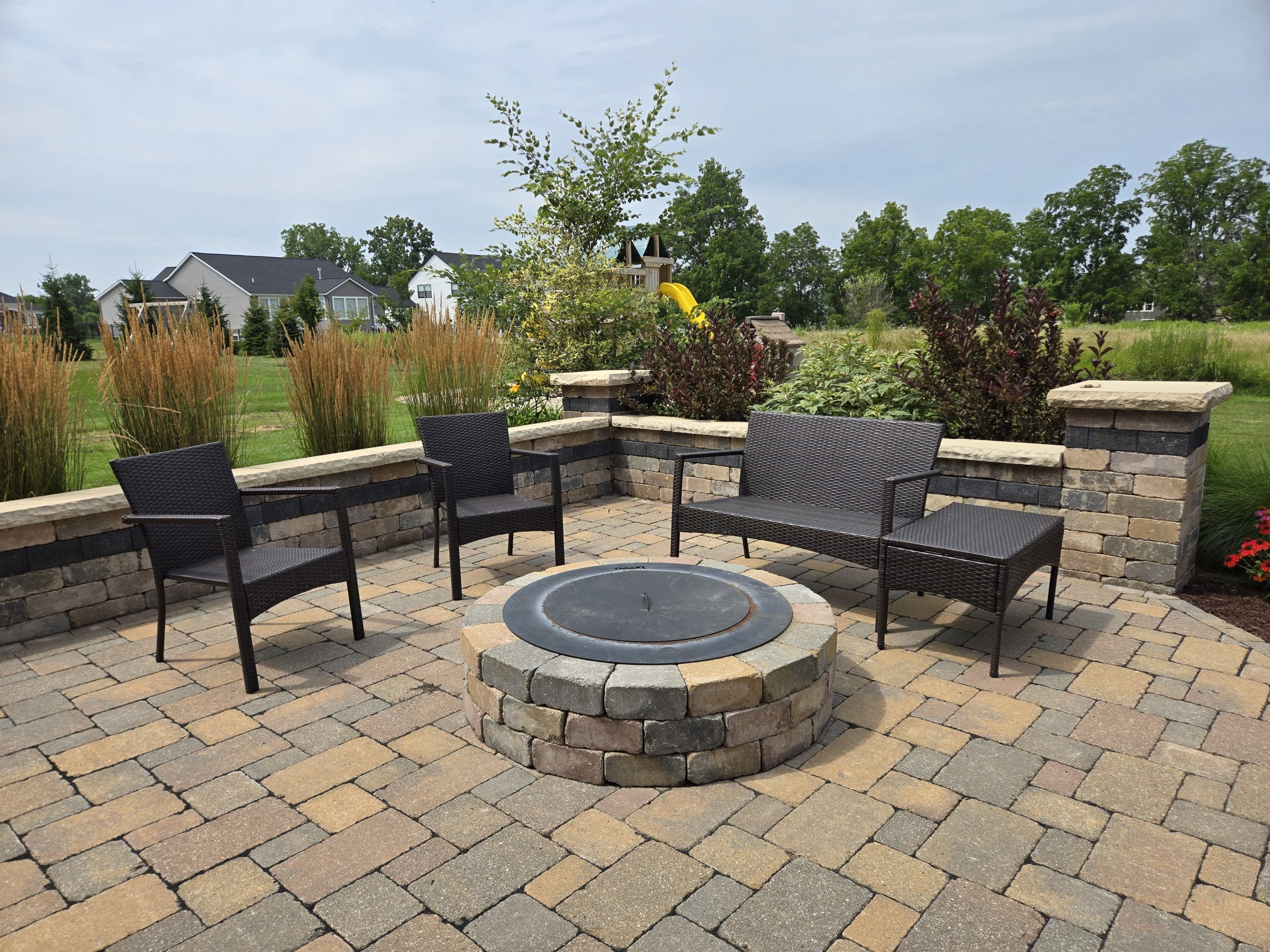 Outdoor patio with fire pit and wicker seating.