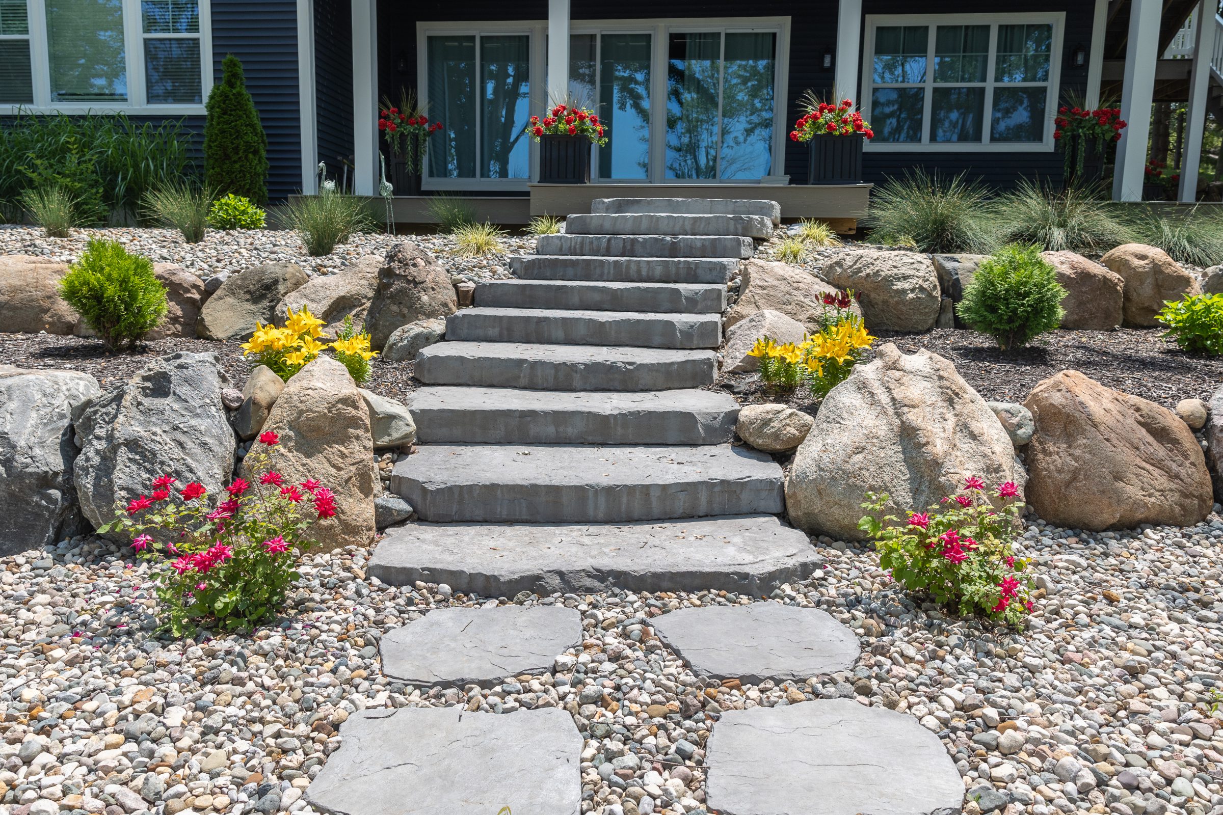 Stone steps lead to house with garden landscape.