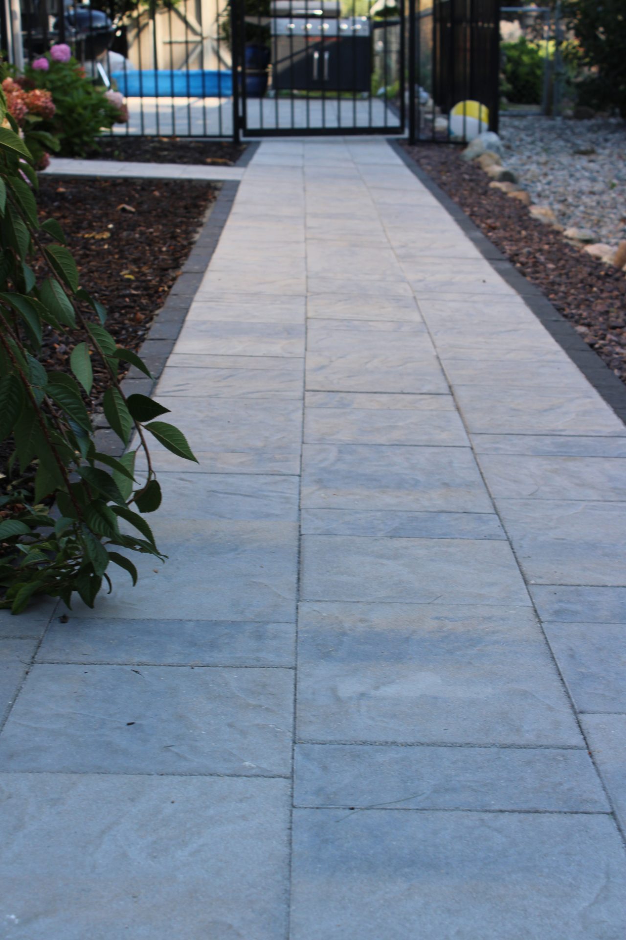 Paved garden path leading to a gated entrance.