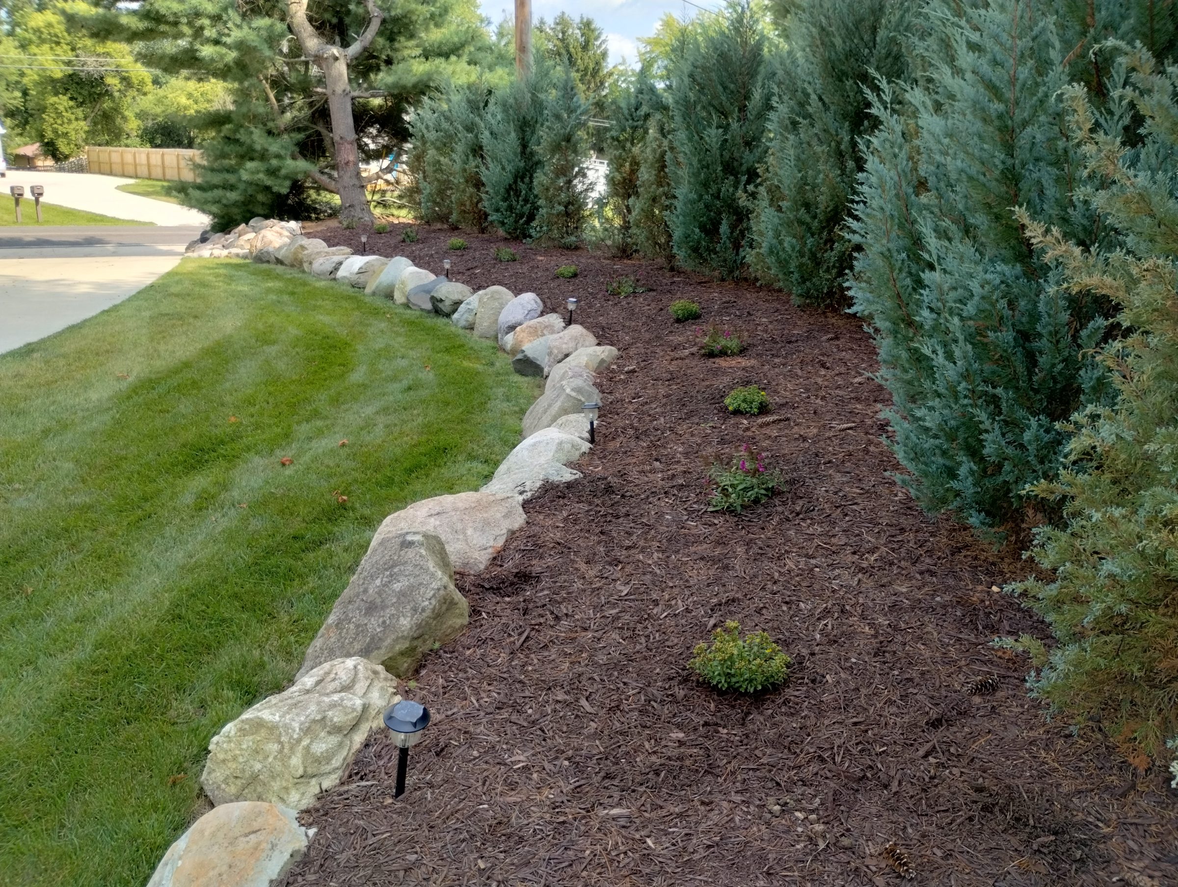 Rock border along trimmed grass and mulch garden.