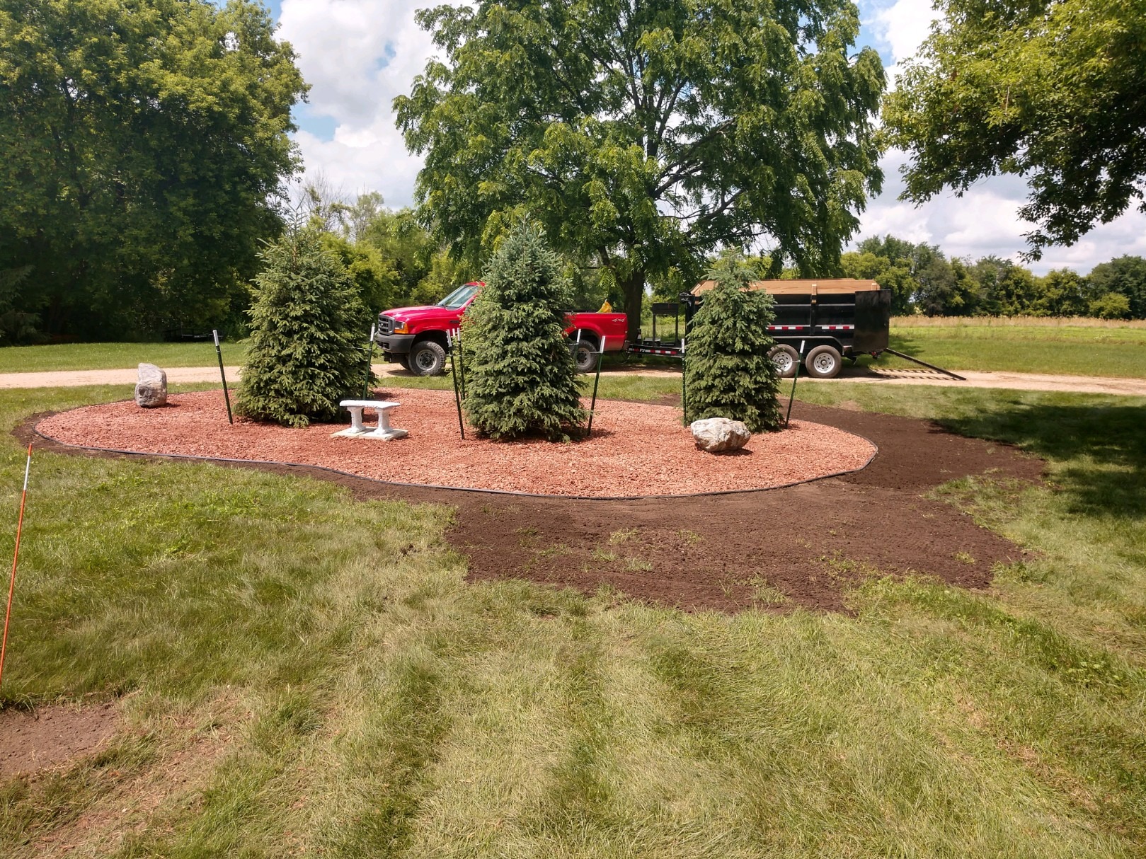 Landscaped area with trees and red truck nearby.