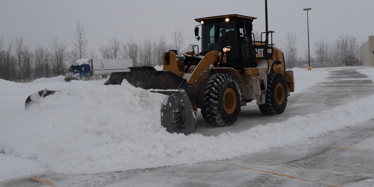 Bulldozer clearing snow from icy road.