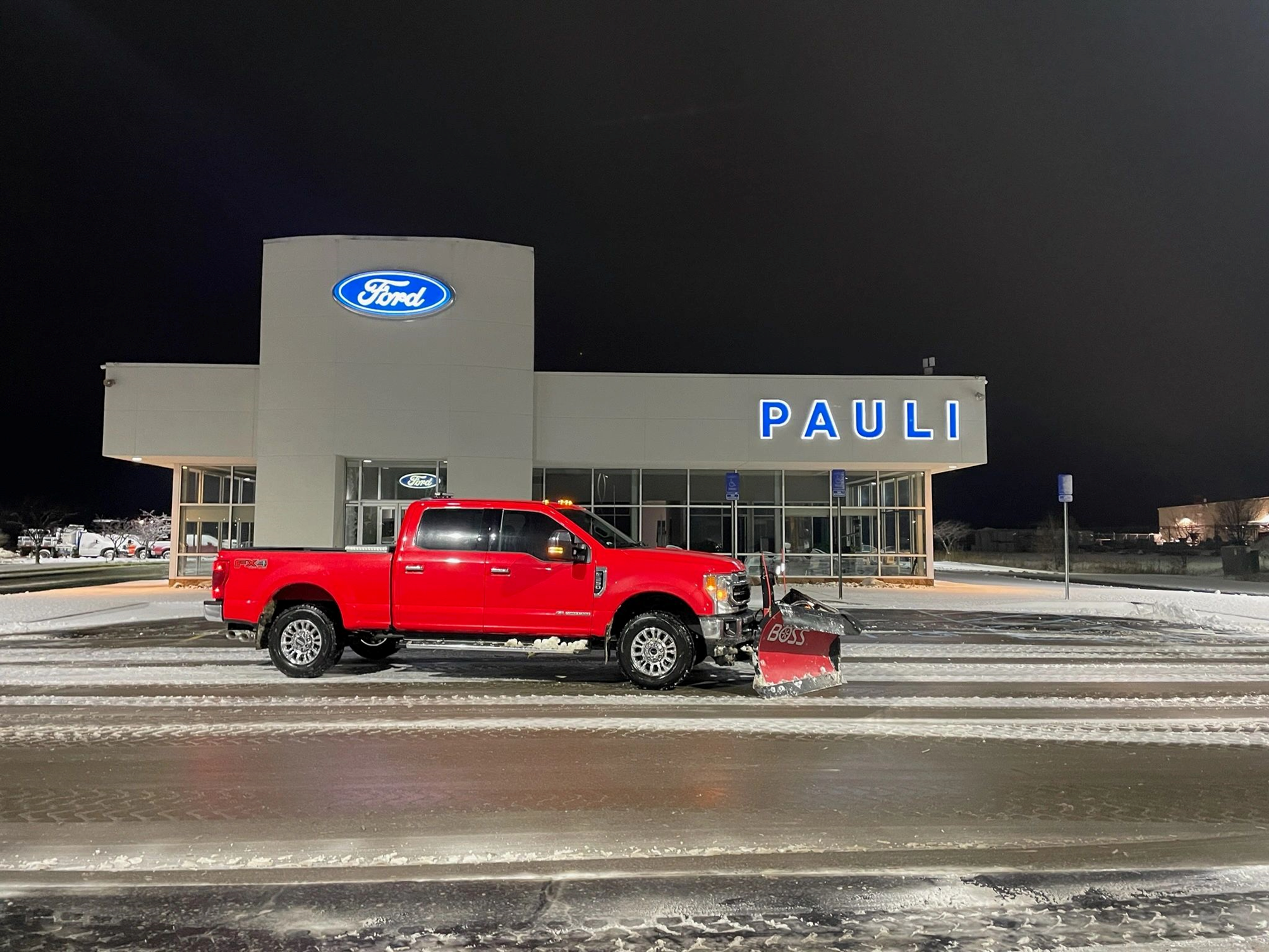 Red truck with snowplow at Ford dealership