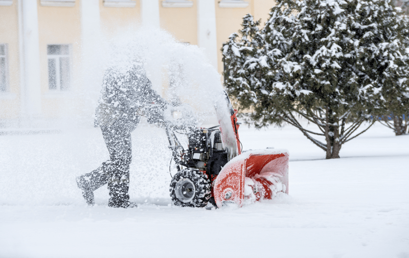 Person using snow blower in snowy yard