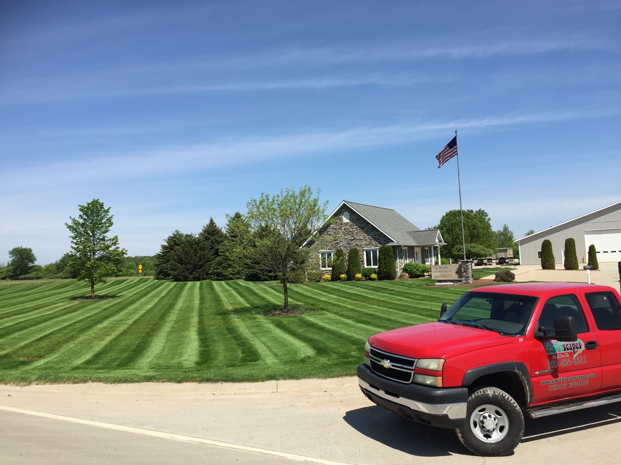 Manicured lawn with red truck in front of house.
