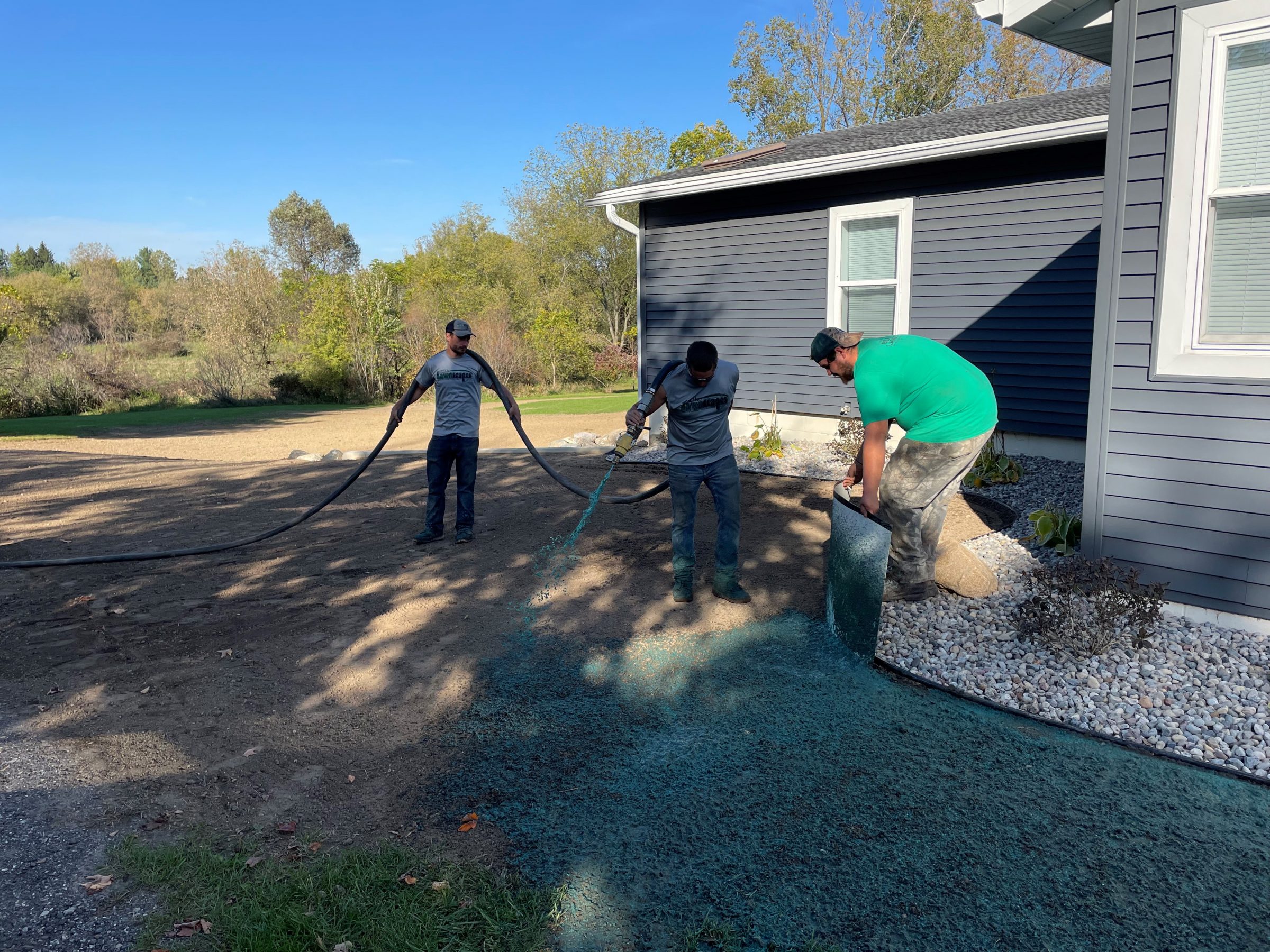 Workers applying hydroseeding near house