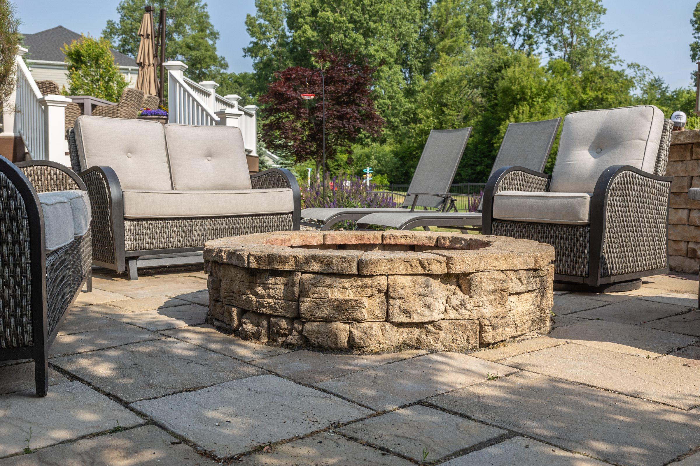 Outdoor patio with stone fire pit and seating.