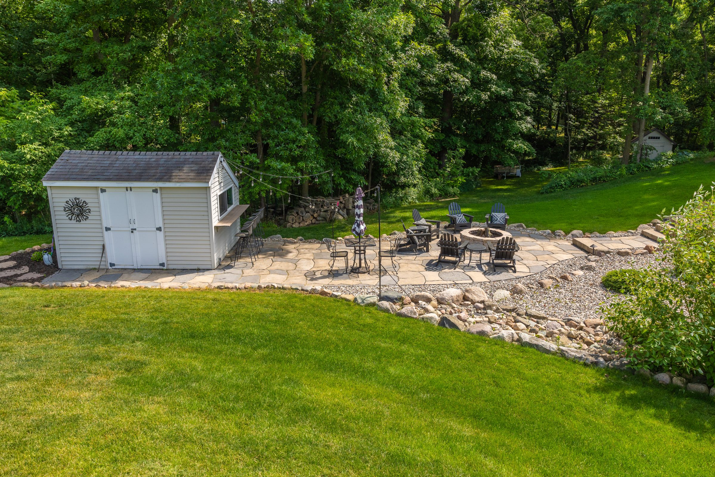 Backyard patio with shed, fire pit, and seating.