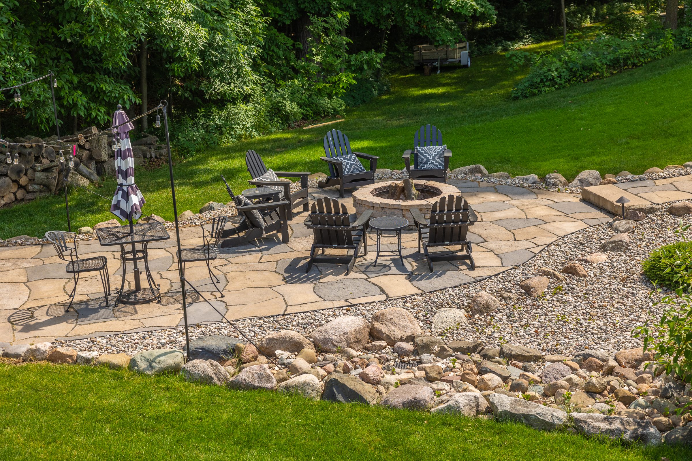 Stone patio with chairs around a fire pit.