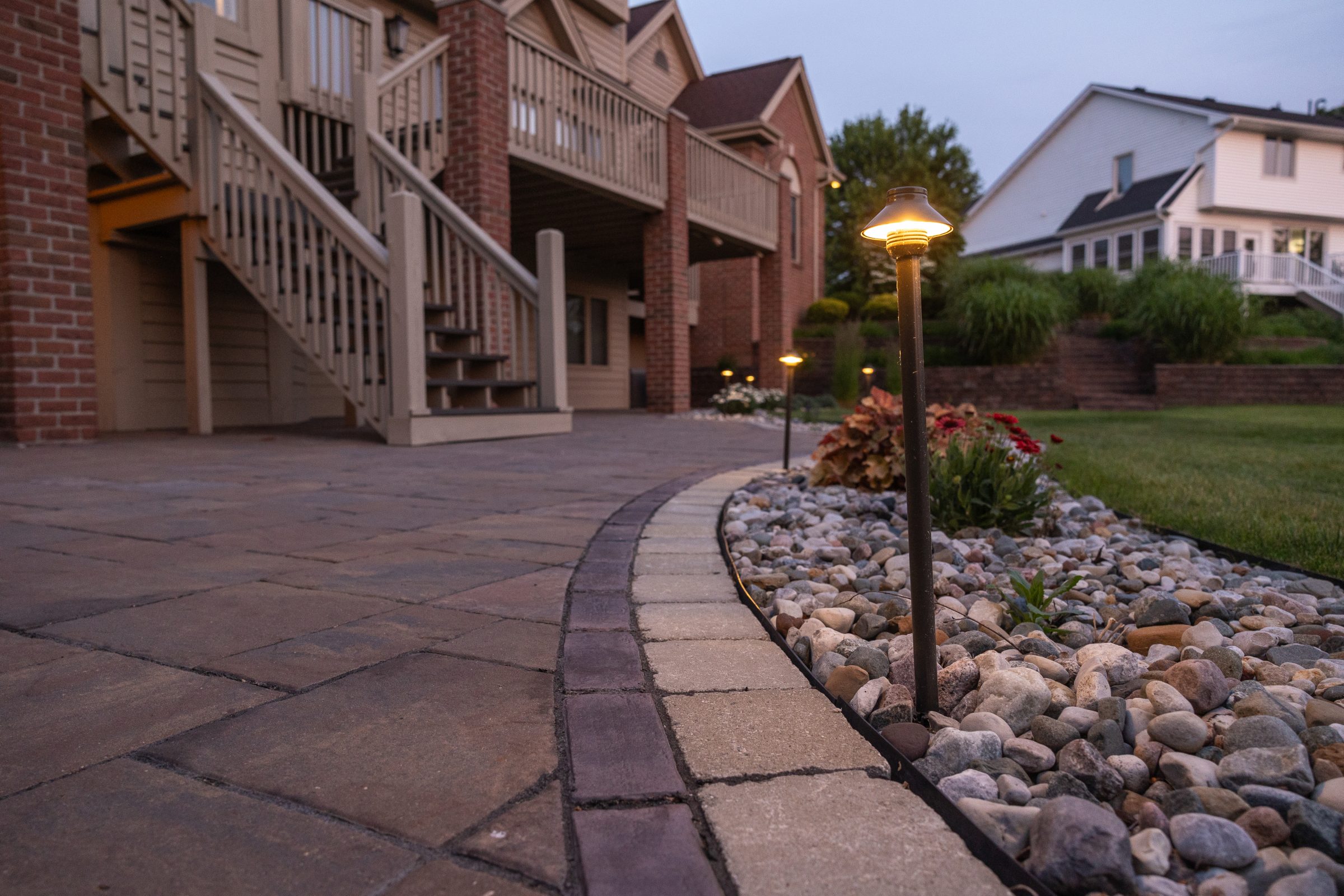 Illuminated backyard patio with garden path and lights.