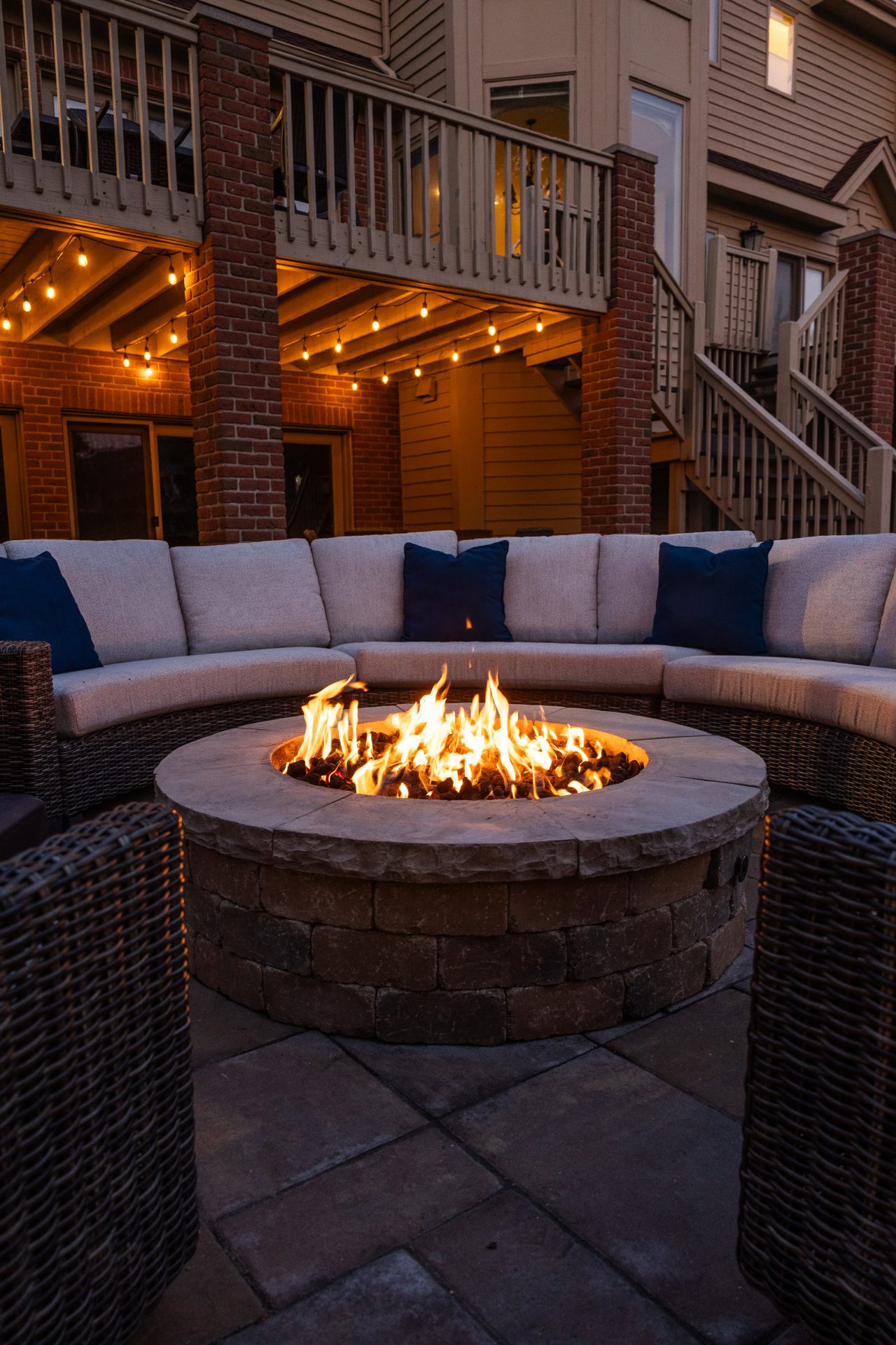 Outdoor fire pit with seating and string lights.