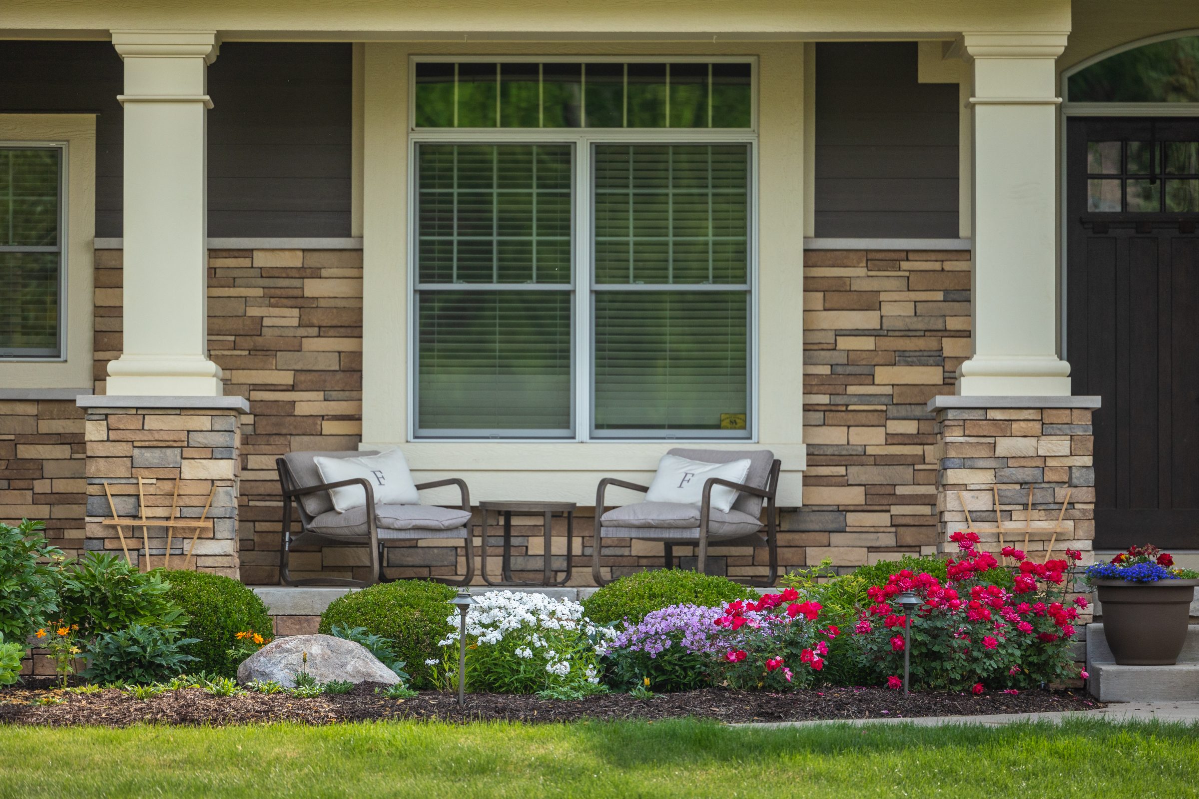 Front porch with chairs and colorful garden flowers.