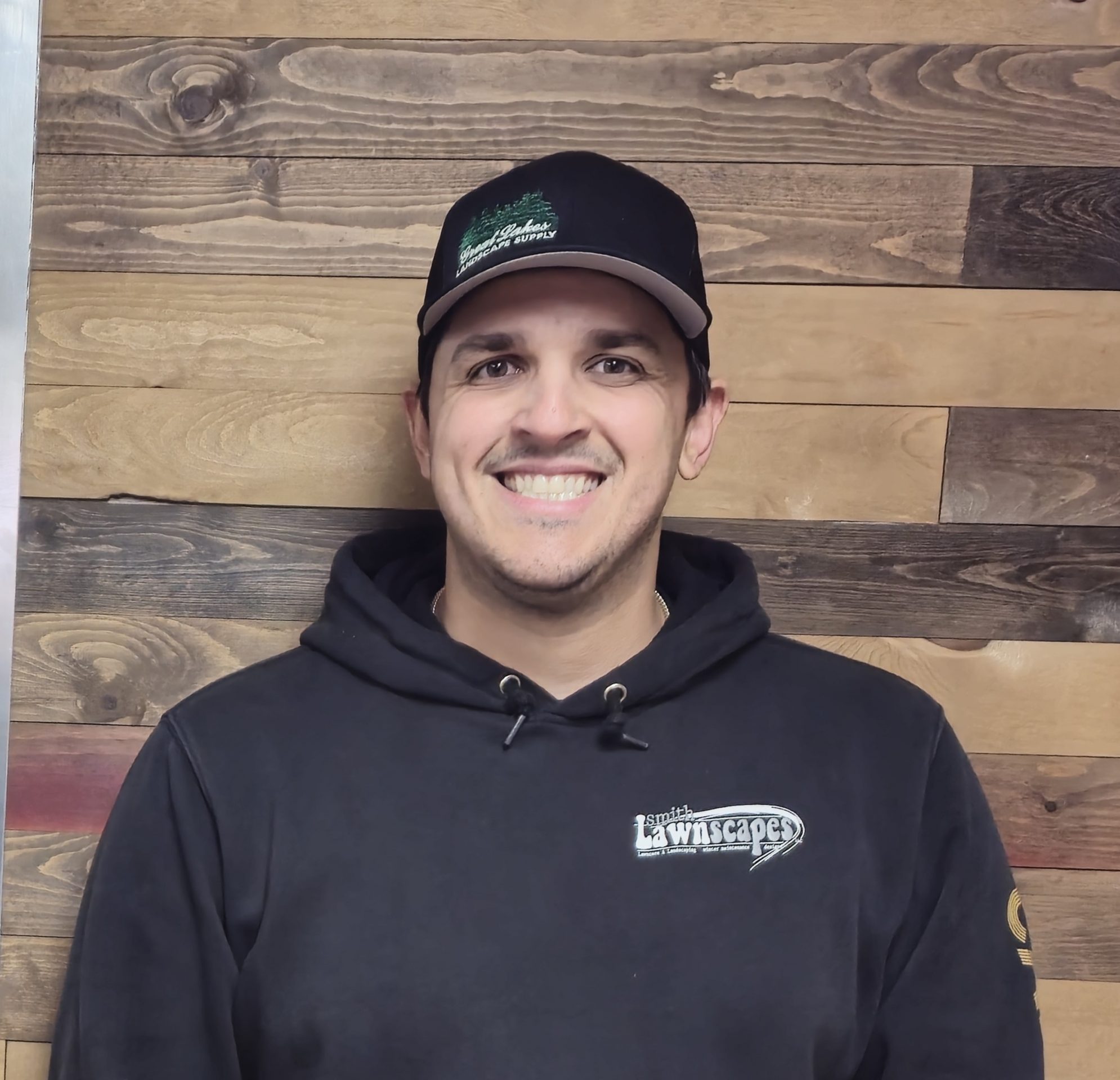Smiling person in black hoodie and cap