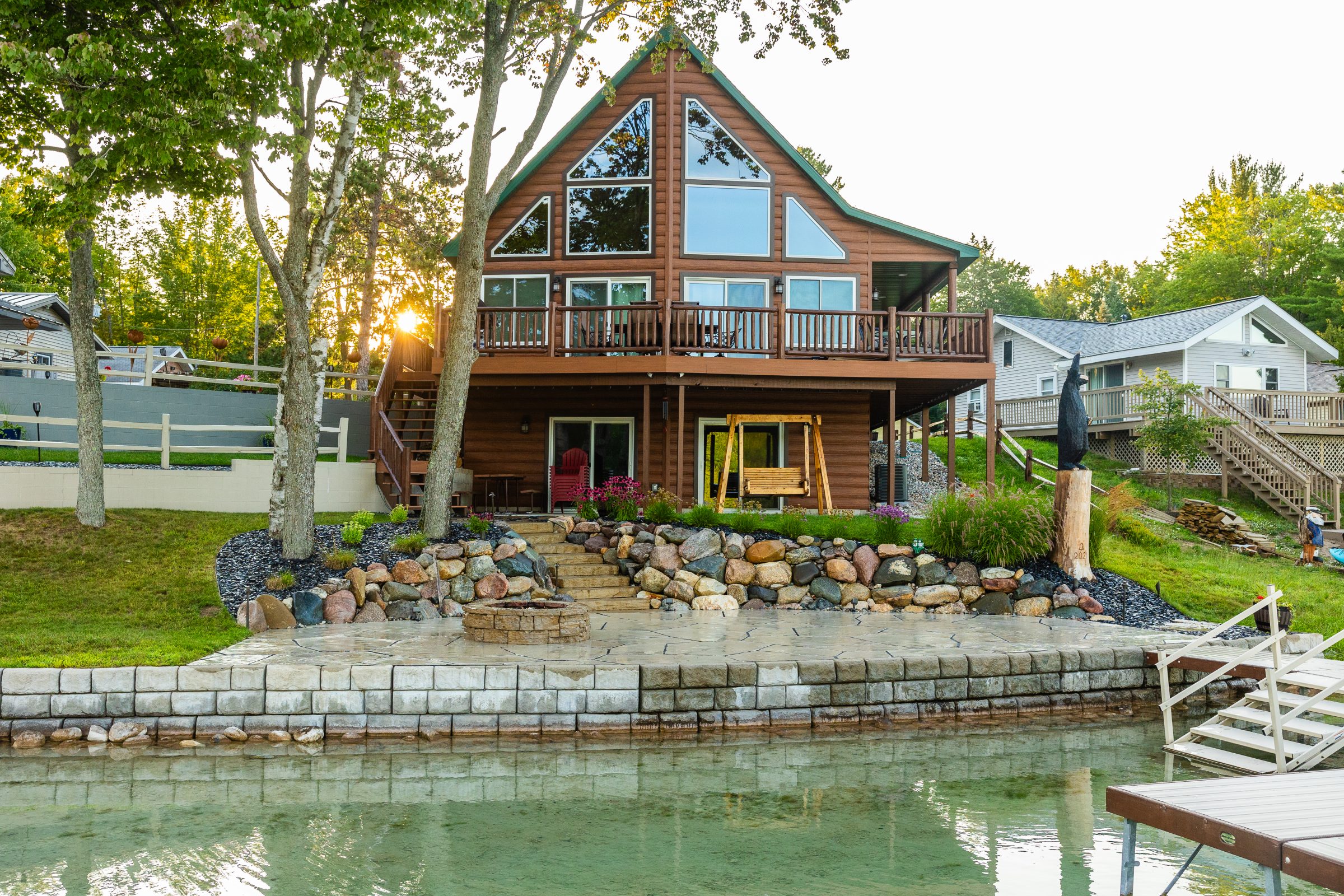 Lakeside cabin with stone landscaping and wooden swing.