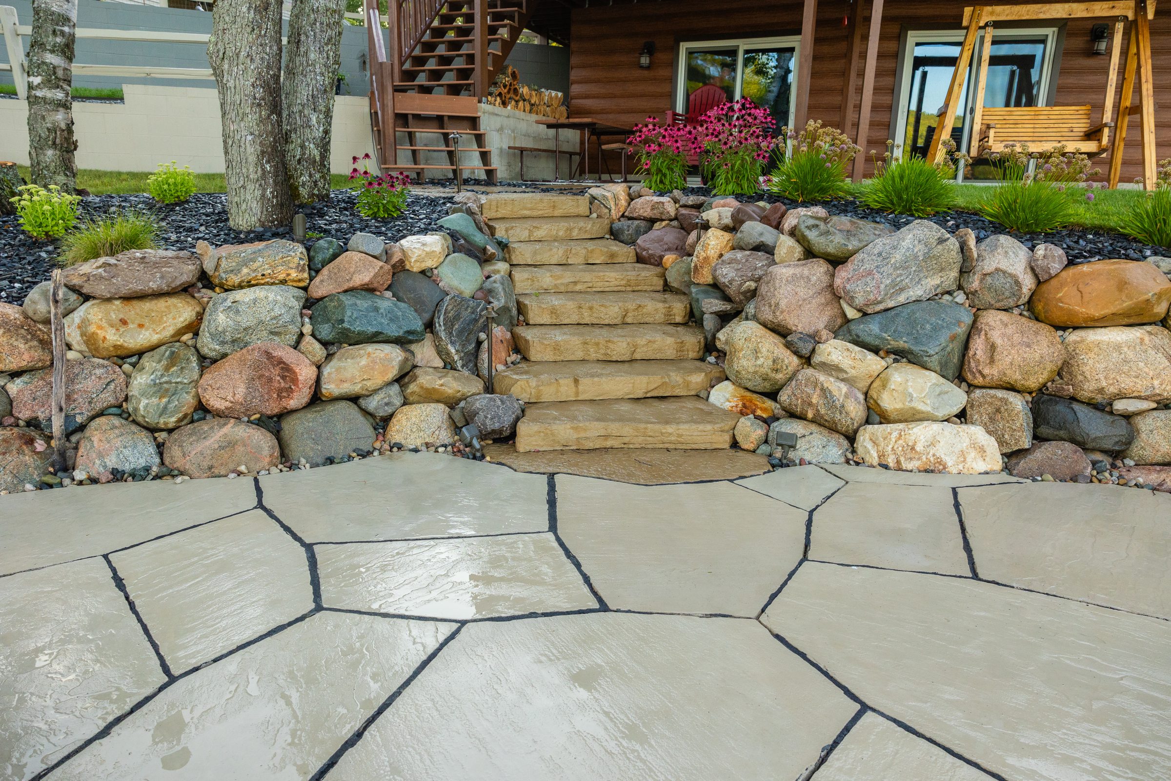 Stone patio with rock retaining wall and steps.