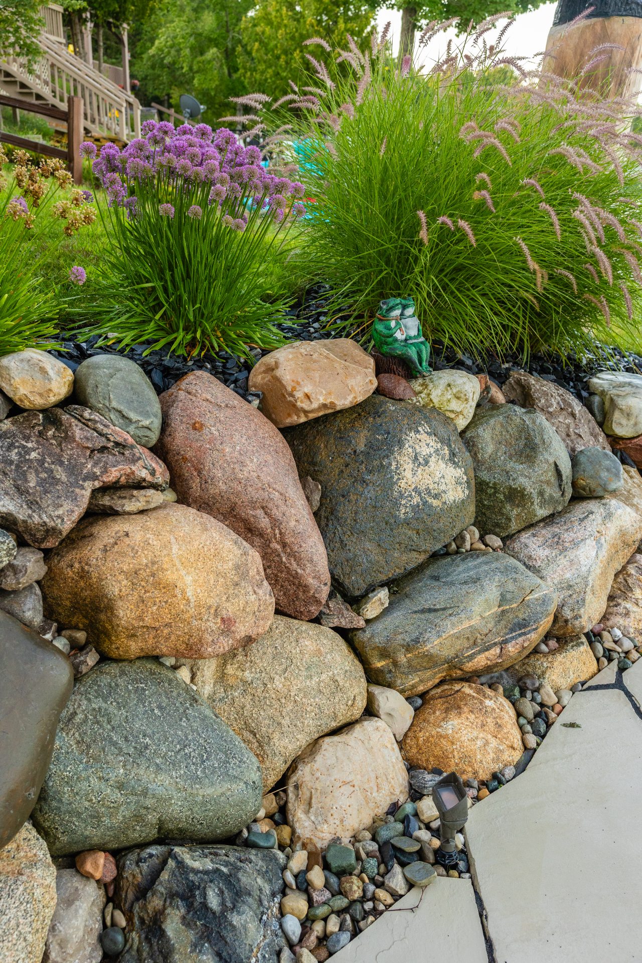 Garden rock wall with flowers and small statue