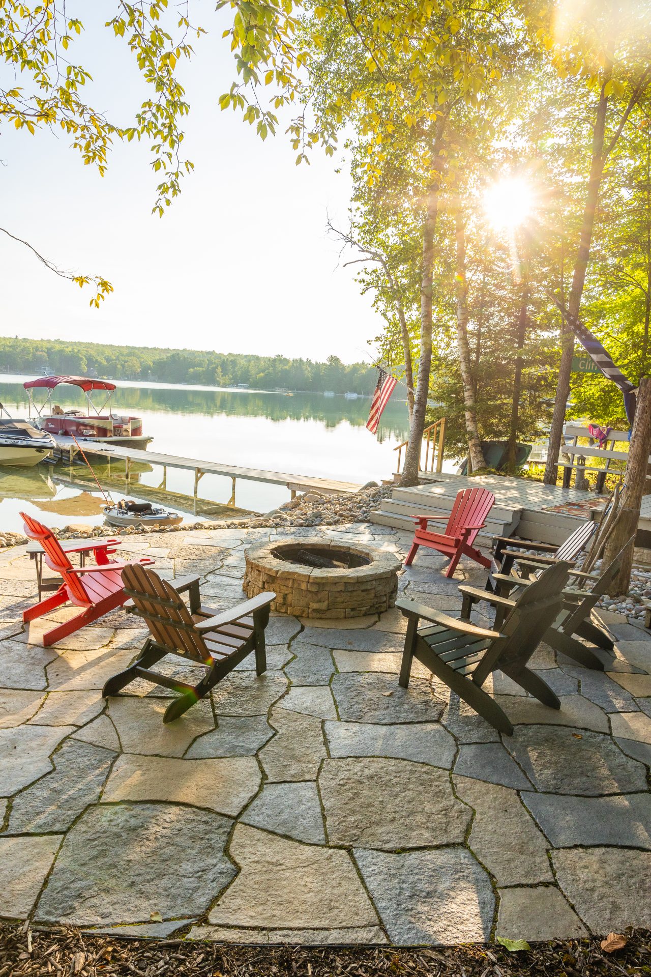 Lakeside patio with chairs and fire pit at sunset.