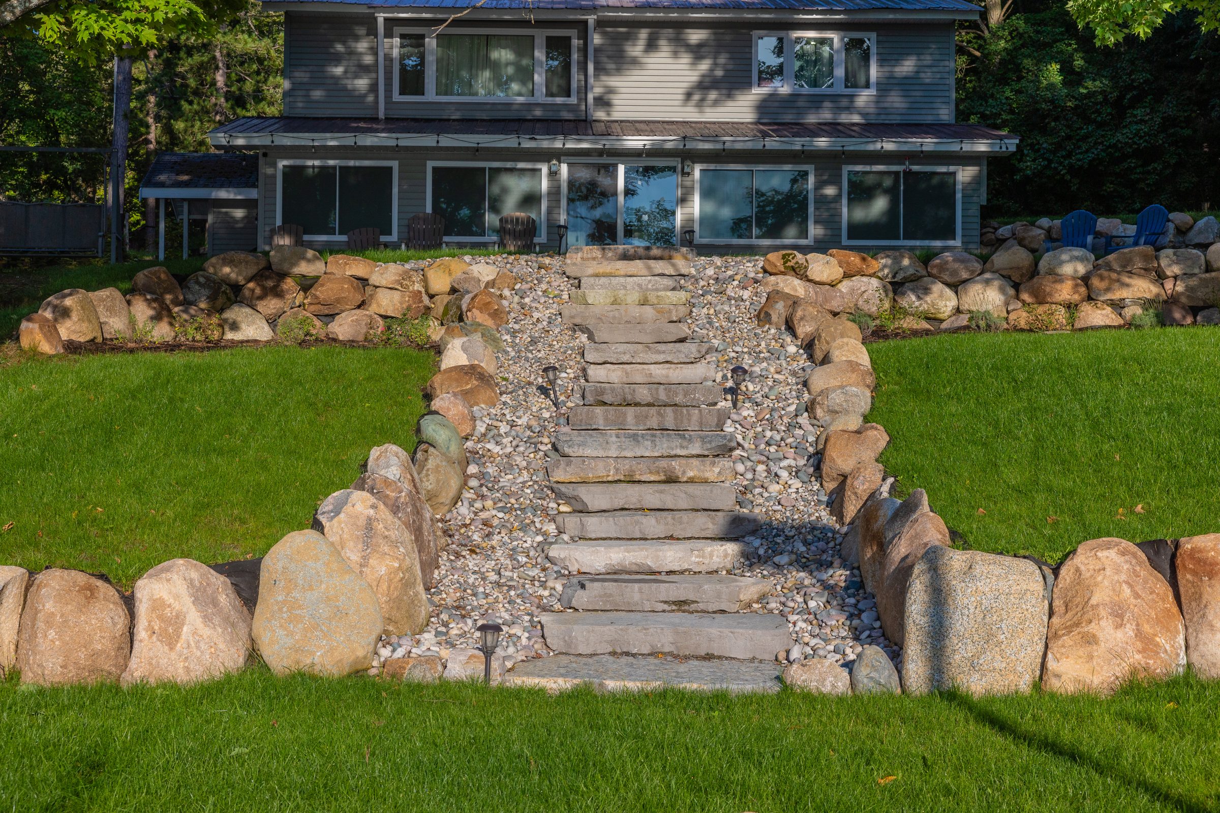 Stone steps leading to a house with green lawn.