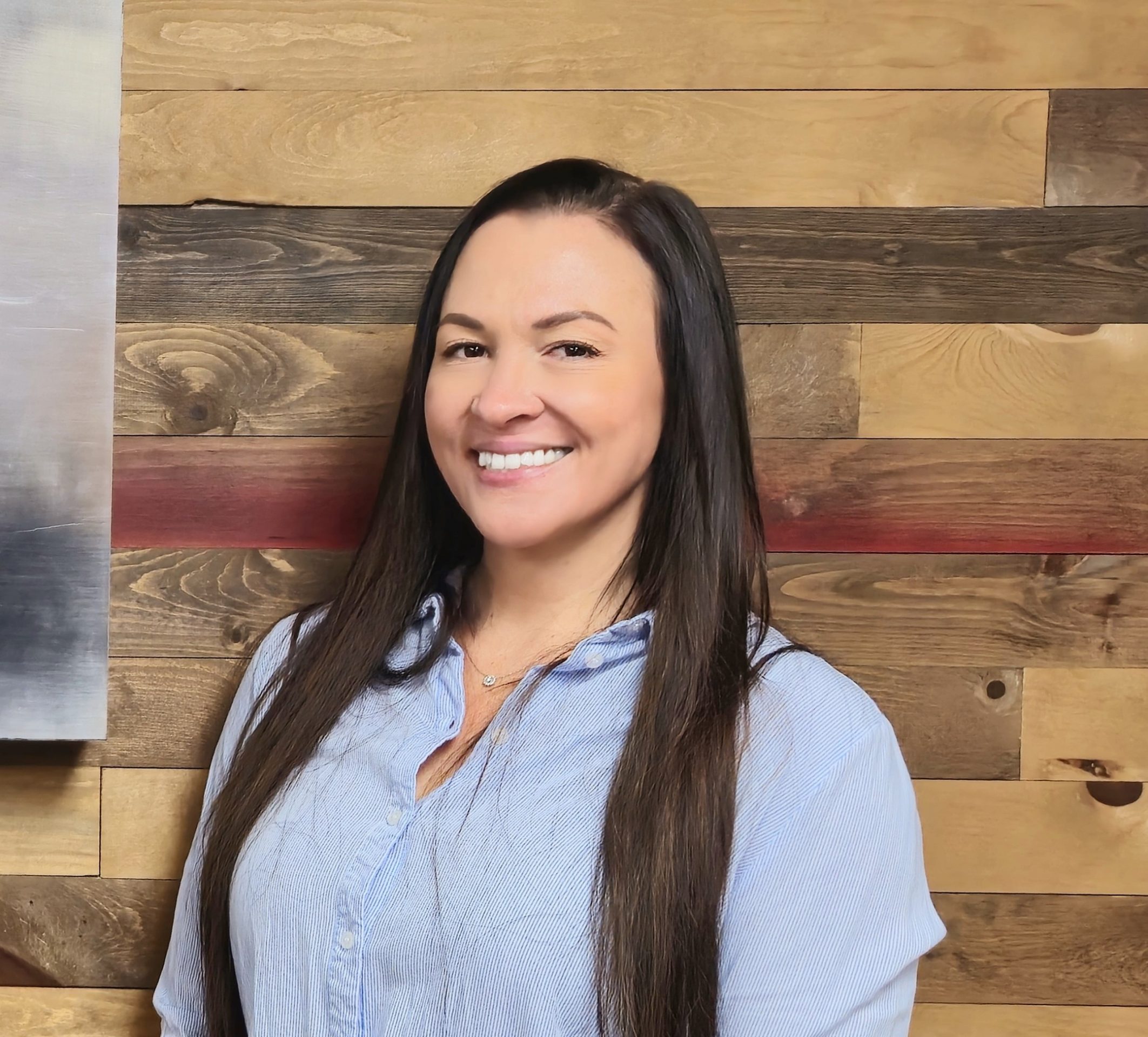 Smiling person in front of wooden wall