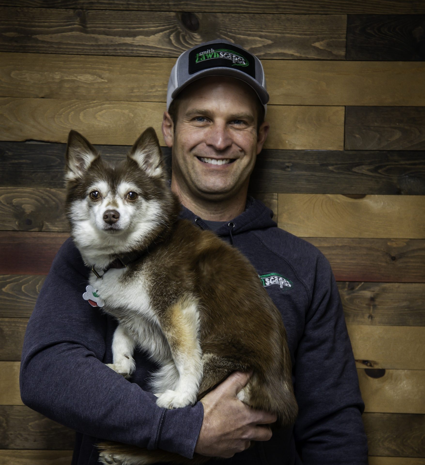 Smiling man holding fluffy dog indoors.