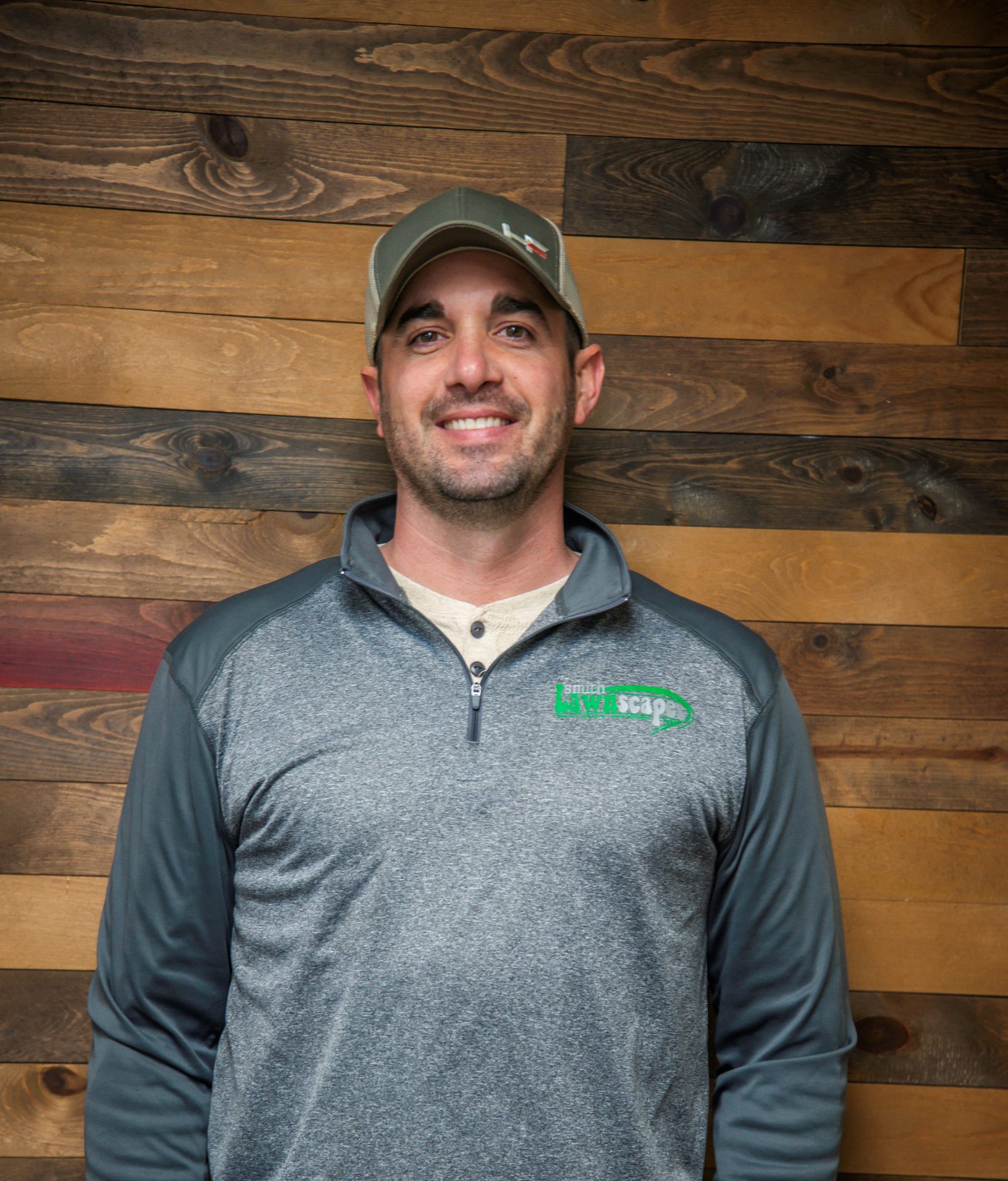Person in gray top with wooden wall backdrop