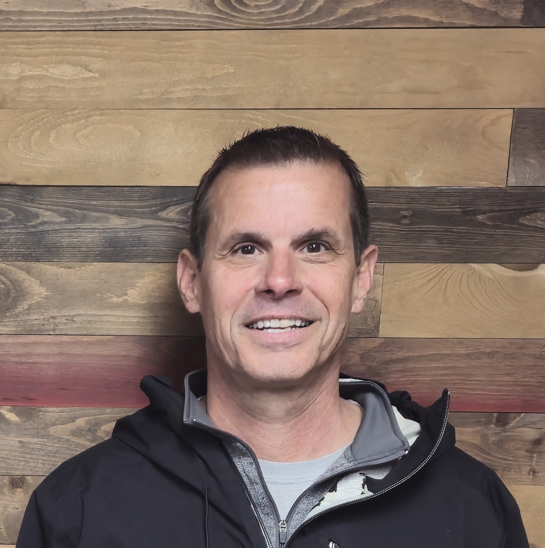 Smiling person in front of wooden wall