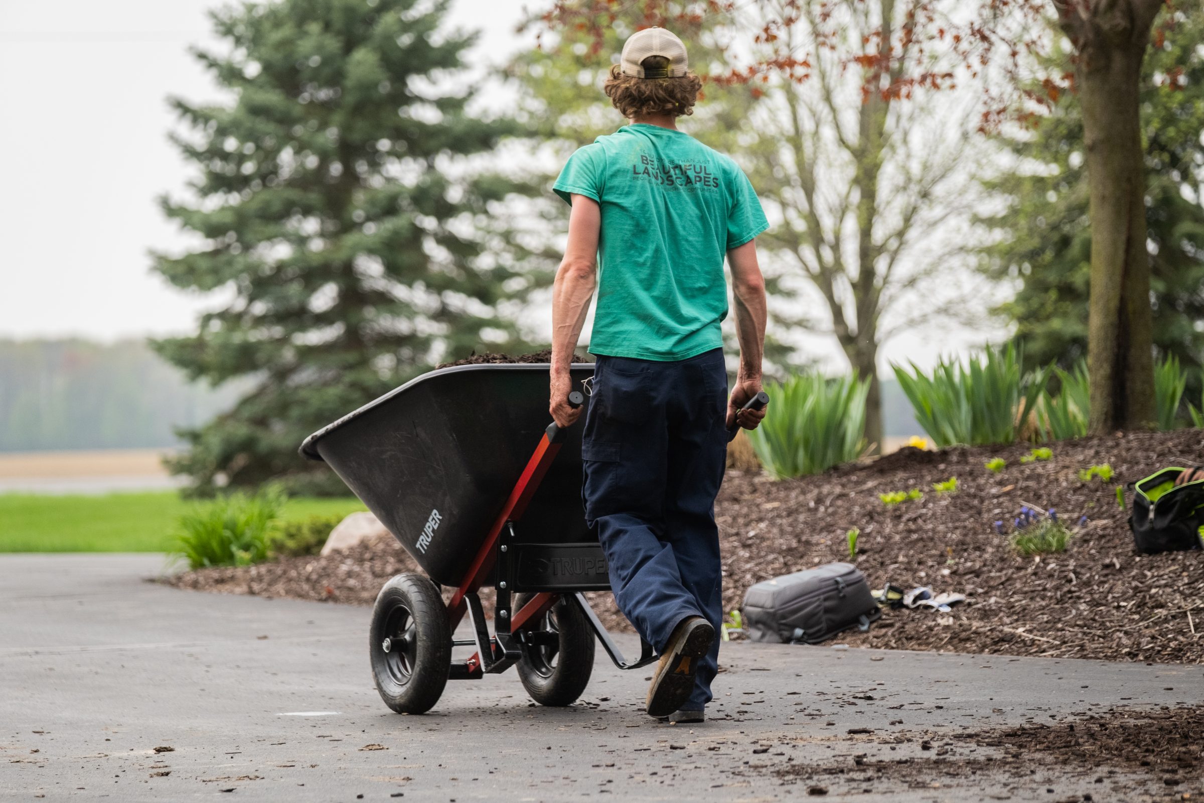 Gardener pushing wheelbarrow on landscaped path