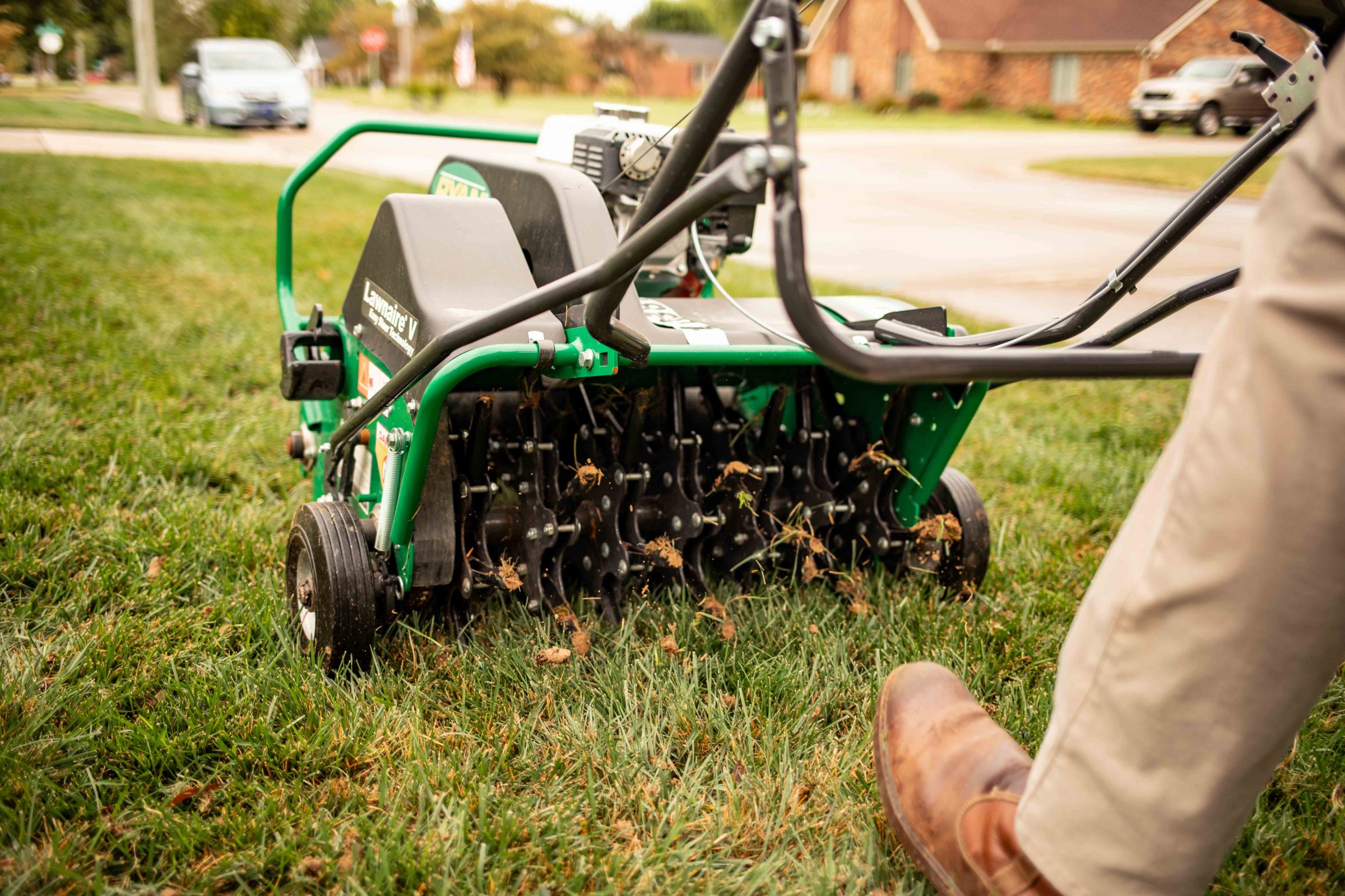Person using lawn aerator on grass.