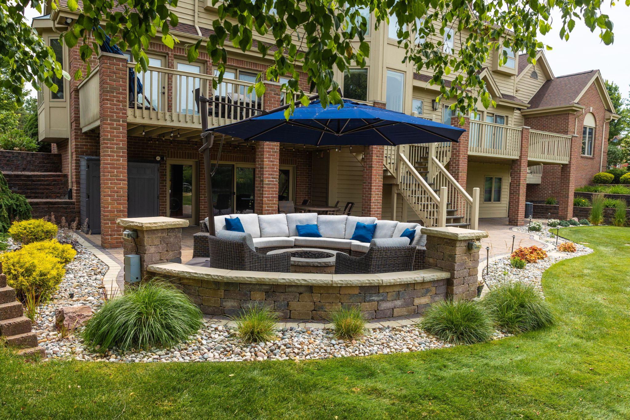 Backyard patio with curved seating wall, umbrella, and fire pit