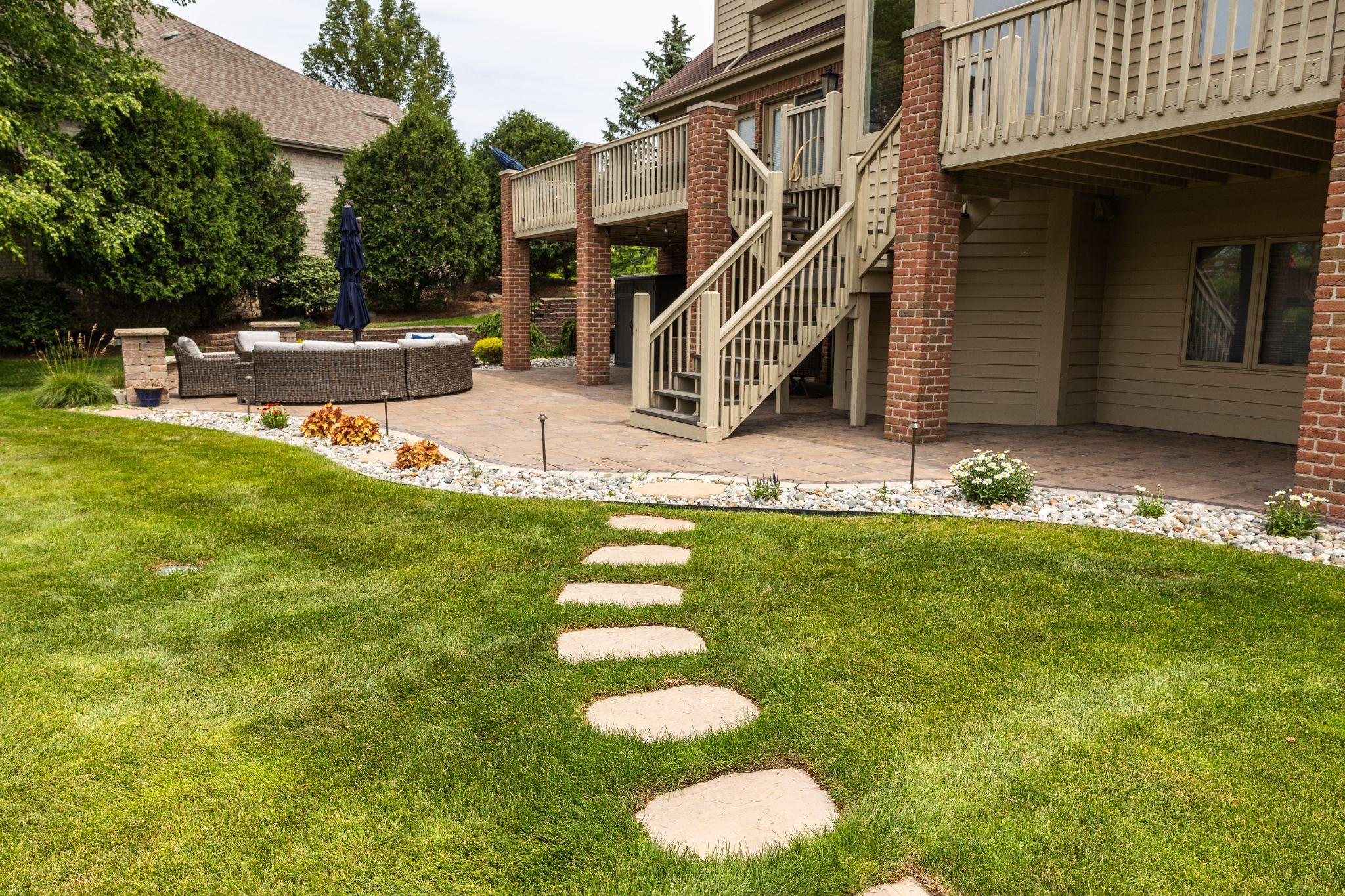 Backyard patio with stepping stone path leading to raised deck