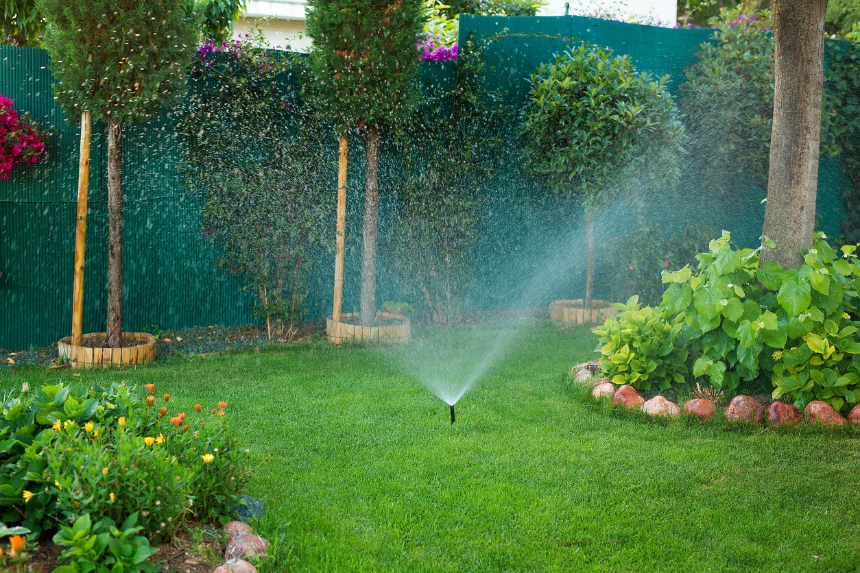 Lush garden with active lawn sprinkler system