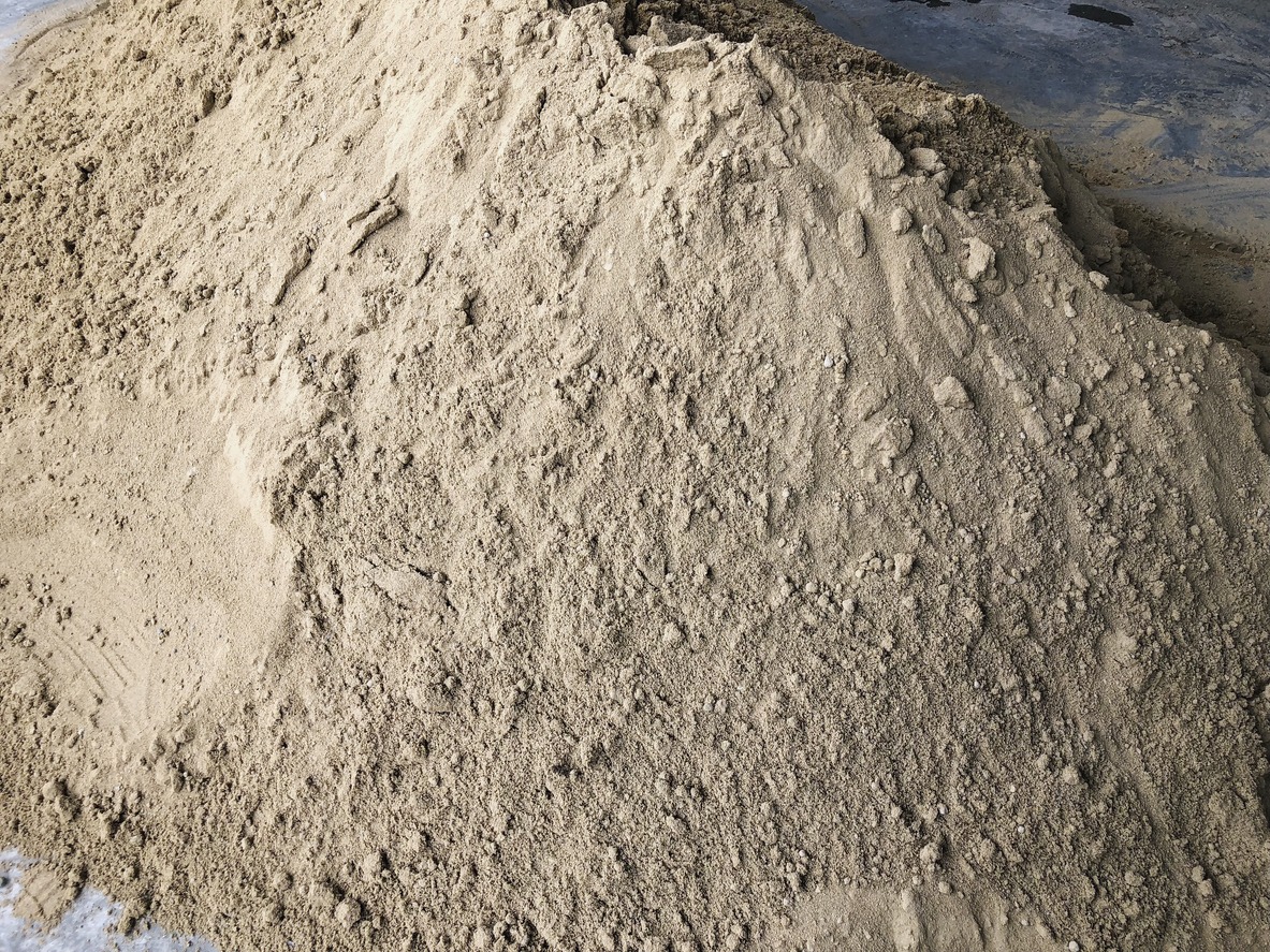 Large pile of sand on concrete floor.