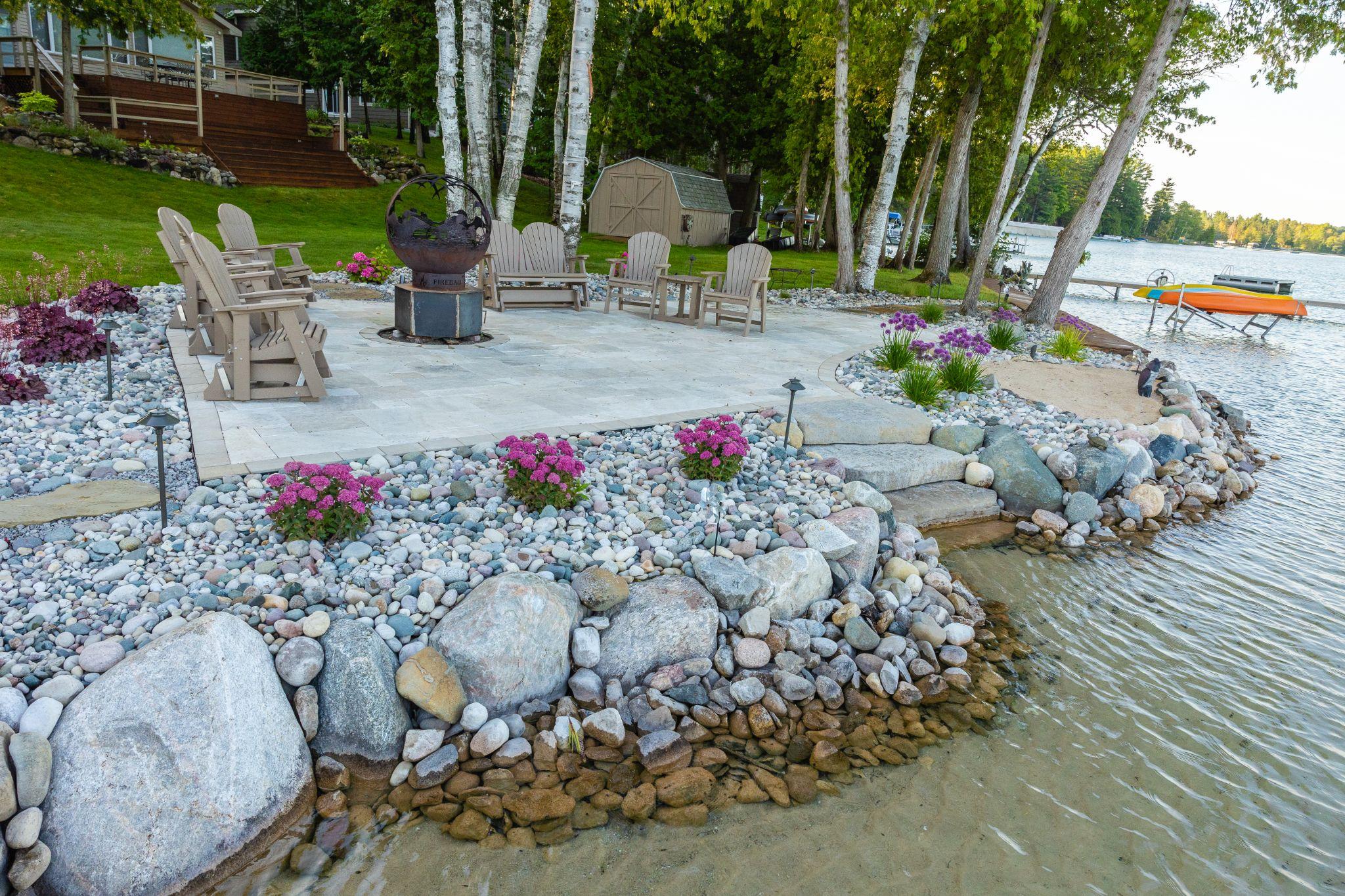 Lakeside patio with fire pit, stone edging, and shoreline plantings