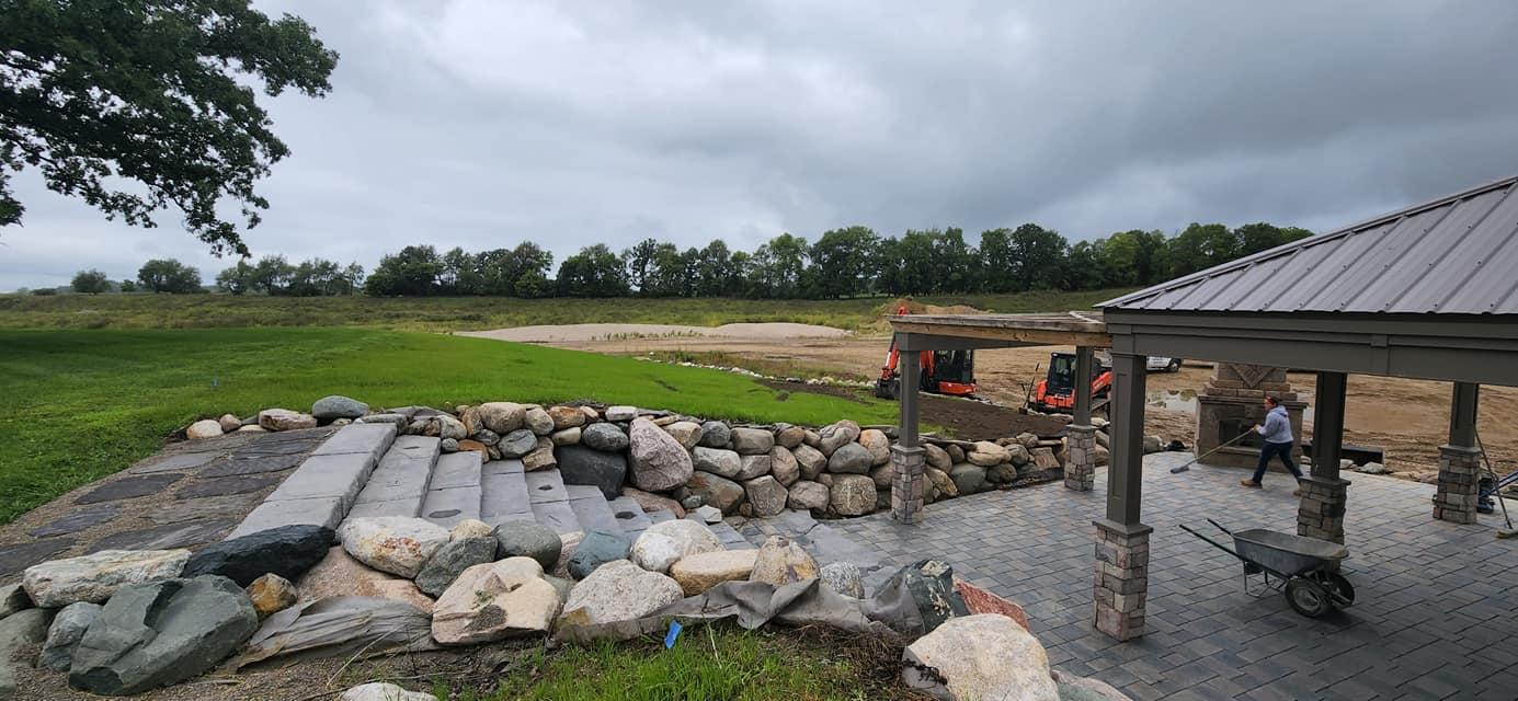 Natural stone retaining wall and paver patio under construction