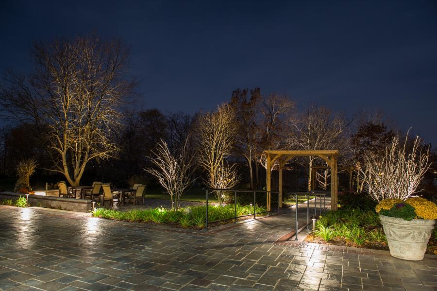 Outdoor patio with pergola and landscape lighting at night