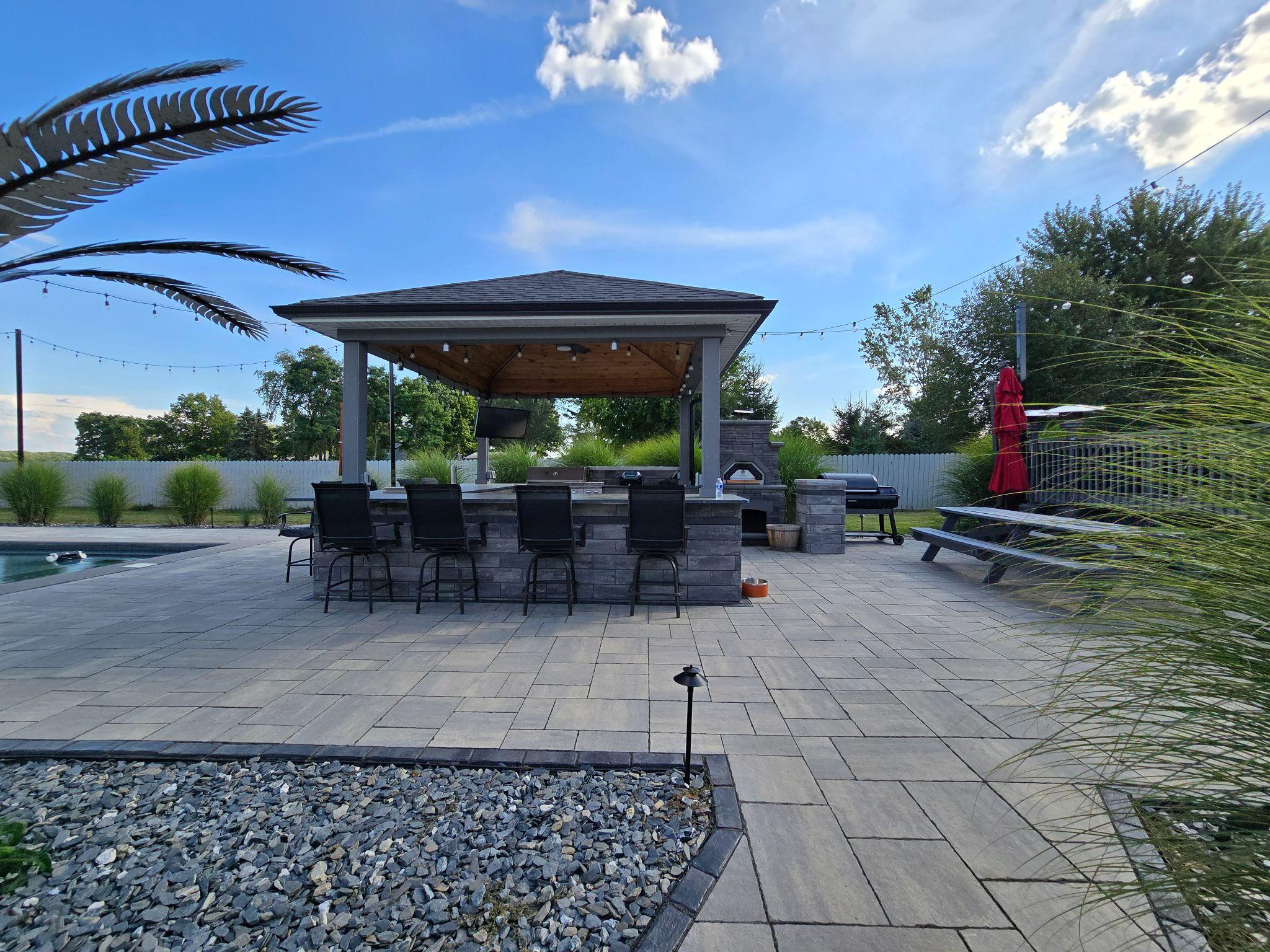 Poolside outdoor bar pavilion with stonework and paver patio
