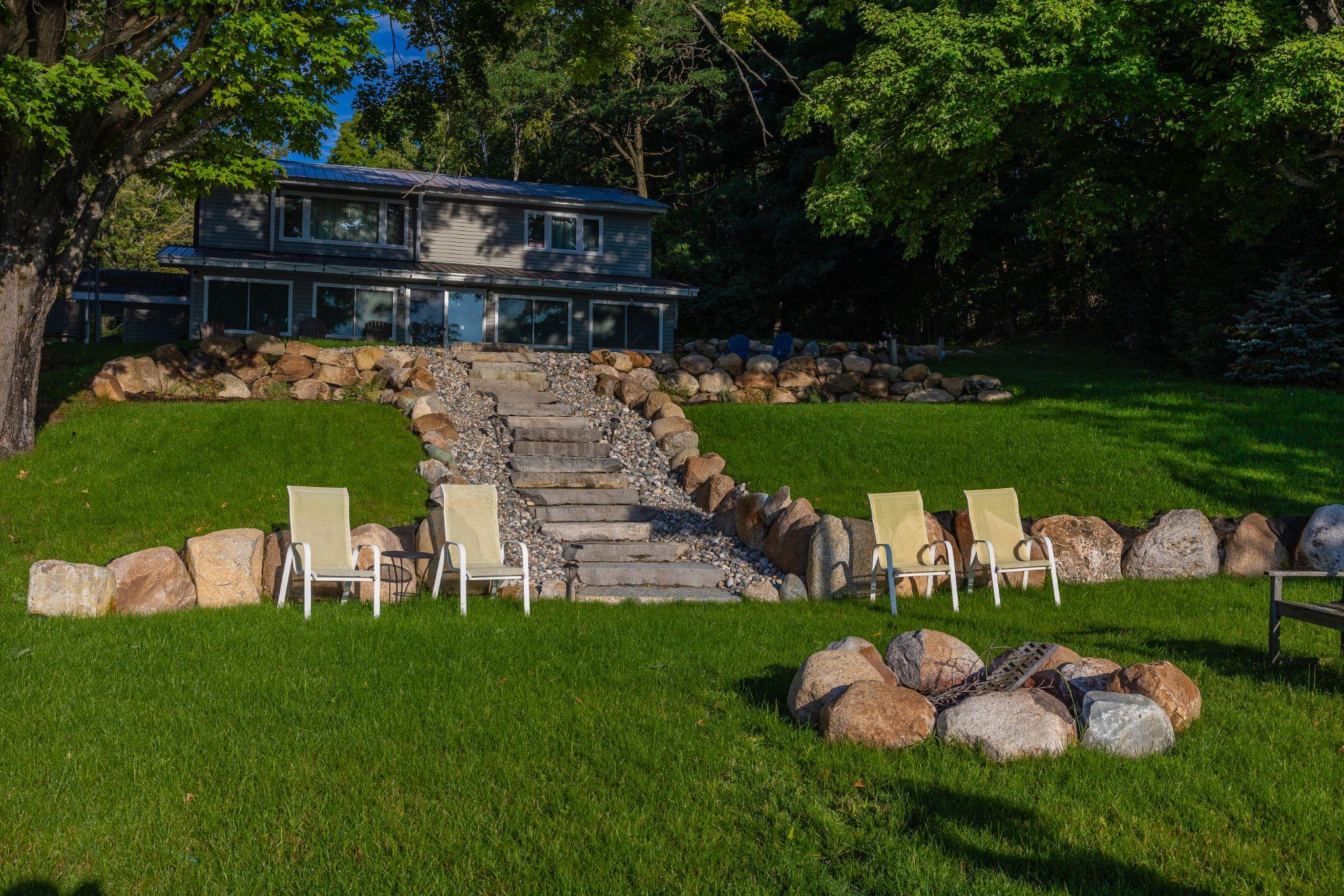Sloped backyard with natural stone steps, seating, and fire pit
